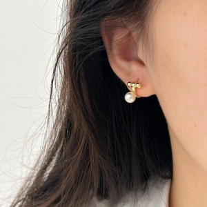 Close-up of minimalist gold pearl stud earring showing 925 silver texture on model