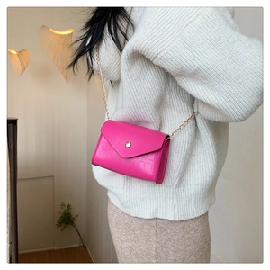 Detailed shot of pink stone textured mini crossbody bag with golden chain strap