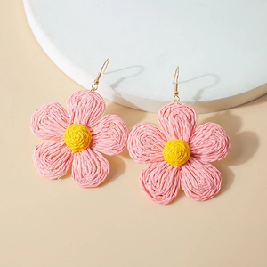 Detail of pink and yellow handmade raffia flower earrings with gold hooks and woven texture