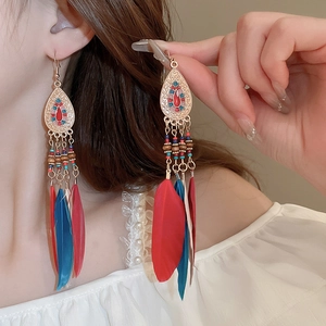 Close-up of Bohemian drop earrings with colorful beads and natural red blue feathers