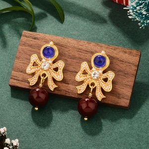 Detailed view of French vintage bow earrings with pearls and wine red beads on green velvet