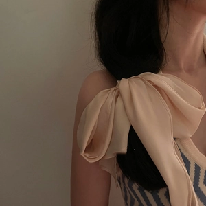 Elegant apricot silk bow scarf tied on shoulder of beige knitted herringbone vest top