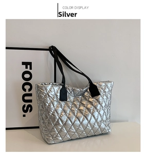 Macro shot of silver quilted tote bag with diamond pattern and black straps