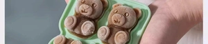 Detail of light green silicone mold showing frozen brown bear-shaped ice cubes with frost