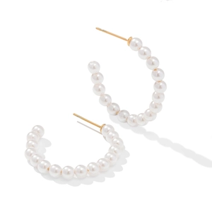 Detailed view of C-shaped hoop earrings with white pearls and gold needles on white background