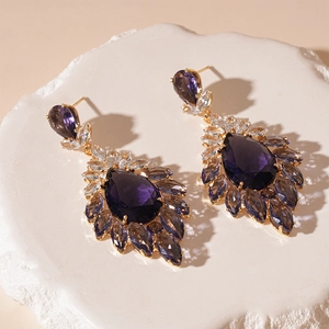 Macro shot of vintage teardrop earrings with purple zircon and golden flower details