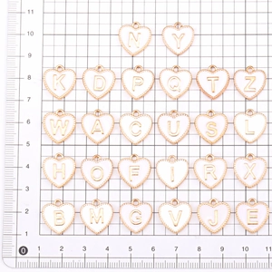 Macro view of white heart-shaped enamel letter charms with gold-plated borders in 1cm size