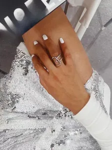 Artistic silver-colored brass ring with fluid streamline design worn on index finger