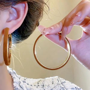 Close-up of brown flocked geometric hoop earrings with gold inner lining detail