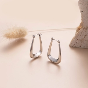 Polished silver geometric trapezoid hoop earrings on a minimalist natural stone background