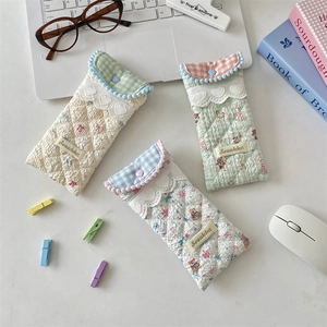Close-up of quilted soft fabric glasses pouches with lace detail and bear patterns