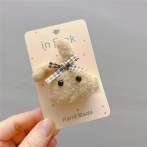Cute light brown plush bunny hair clip with plaid bow displayed on a pink card