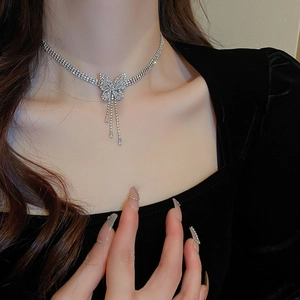 Détail du collier papillon argenté avec glands en zircon sur le cou d'un mannequin