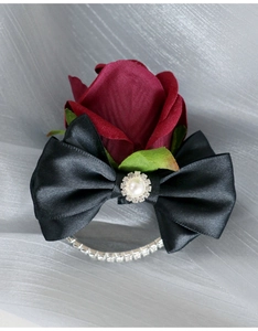 Detail of dark red artificial rose wrist corsage with black satin bow and pearl accent