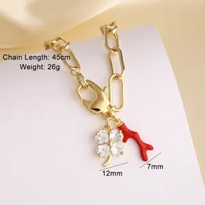 Detail van gouden ketting met 12mm klaver zirkoon en 7mm rode koralen hanger