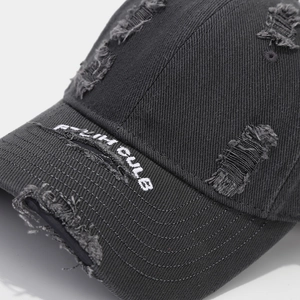 Detailed close-up of distressed cotton baseball cap with white 3D embroidery and worn brim