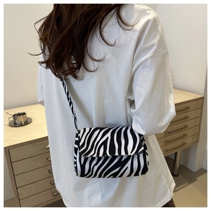 Detail of a chic zebra print crossbody bag on a model in a casual indoor setting