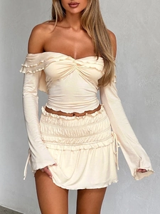 Detailed close-up of beige textured long sleeve top with ruffles and drawstring skirt