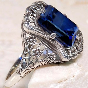 Vue macro de face d'une bague vintage en argent avec gemme bleue et ciselures florales