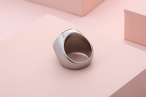 Macro detail of men silver stainless steel ring with textured brown inlay on pink stand