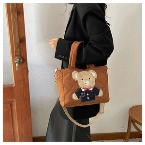 Detail of brown quilted bear tote bag featuring embroidery and beige shoulder strap