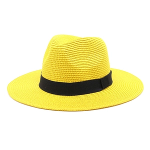 Close-up of bright yellow straw fedora featuring fine woven texture and black ribbon band