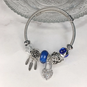 Dettaglio del bracciale argento con acchiappasogni, lucchetto a cuore e ciondoli blu