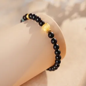 Ethnic style black sandalwood bead bracelet with yellow amber centerpiece and gold accents
