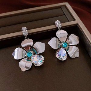 Detailed close-up of silver flower earrings with blue stone and teardrop crystal