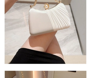 Detail of elegant cream satin pleated evening bag with pearl clasp and gold handle