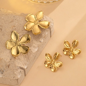 Macro detail of gold flower earrings showing 3D textured petals and metallic finish