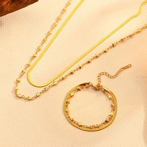 Détail de parure collier et bracelet double couche dorés avec breloques cœur et étoile