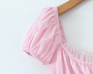 Detailed close-up of pink and white striped dress with puff sleeves and pleated square neck