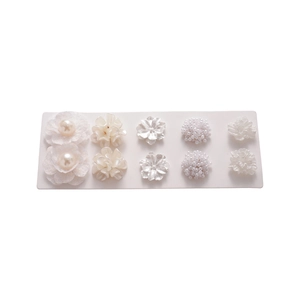 10-piece set of elegant white acrylic flower and faux pearl stud earrings on white display