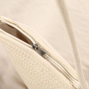 Close-up of beige woven shell bag showing metal zipper closure and knit texture