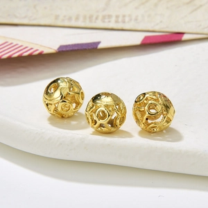 Macro shot of three hollow golden round beads with circular cutout texture for DIY jewelry
