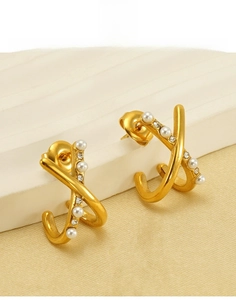 Close-up of gold titanium steel X-shaped earrings with pearls and crystals