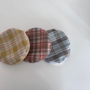 Detailed view of three checkered wool berets in yellow, red, and blue grey plaid textures