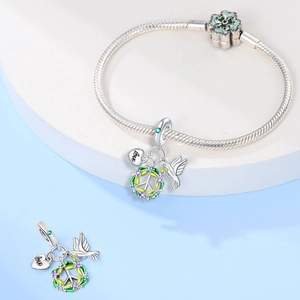 Dettaglio di ciondoli in argento con colomba e cuore su un bracciale con chiusura a trifoglio