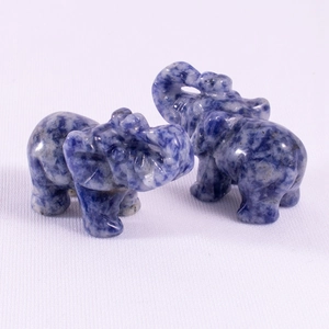 Detail of two hand-carved blue and white spotted gemstone elephant figurines on fabric