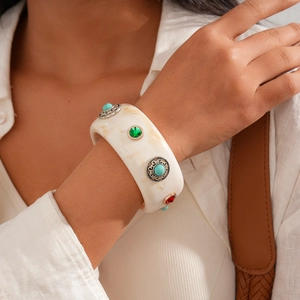 Detail of vintage marble resin cuff bracelet with turquoise and emerald stone inlays