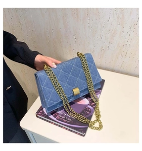 Detail of blue denim crossbody bag with white diamond stitching and gold chain