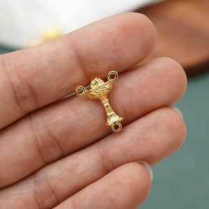 Macro shot of gold-tone IHS religious chalice charms for DIY rosary jewelry making