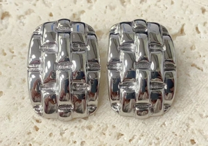 Detail of silver titanium steel earrings featuring a textured geometric woven square design