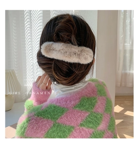 Detail of beige plush hair claw clip worn on a model back view for elegant hair styling