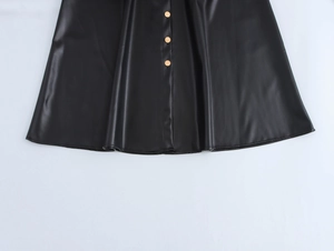 Detailed view of black PU leather skirt hem with decorative golden buttons and pleats