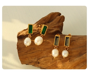 Detail of gold titanium steel earrings with black and green zircon and fresh water pearls