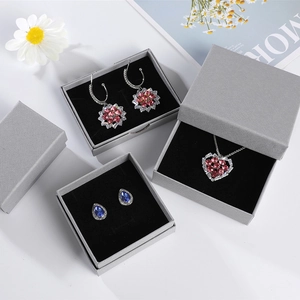 Detail of pink floral earrings and crystal necklace in gray textured jewelry boxes