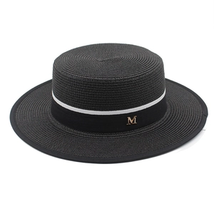 Detailed macro view of black boater hat with striped ribbon and gold M metal logo