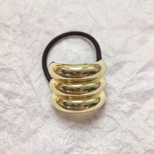 Macro shot of minimalist gold triple-layered ring hair tie with black elastic band texture